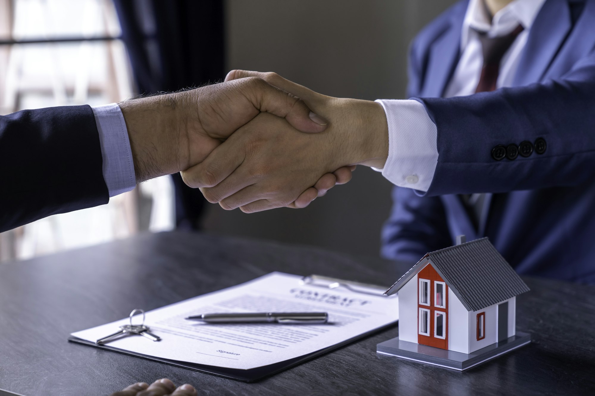 Real estate brokers are shaking hands to congratulate buyers after agreeing to insure and buy a hous